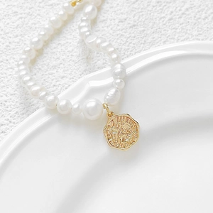 Baroque pearl necklace with 18k gold plated rose pendant on white ceramic bowl