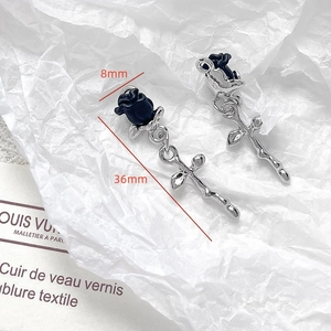 Macro shot of gothic black rose earrings with silver thorn details and size markings