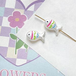 Detail of hand-painted fish beads in pearl white with colorful stripes for DIY jewelry making