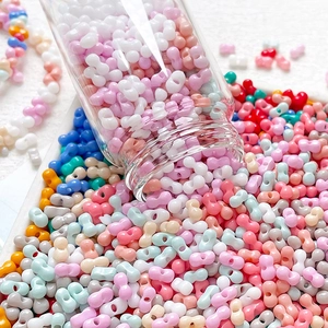 Macro view of colorful resin bow-tie and dumbbell beads pouring from a glass jar