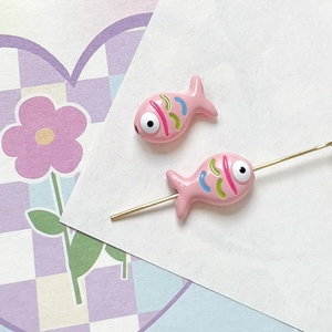 Macro detail of a hand-painted pink fish-shaped bead for DIY jewelry making