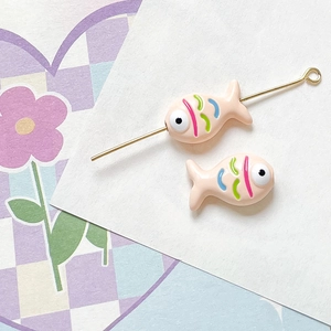 Detailed view of hand-painted fish beads with hollow perforation for DIY jewelry making