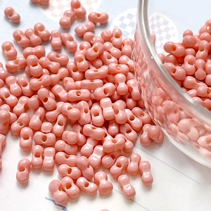 Macro detail of glossy peach-pink double-hole dumbbell beads for DIY jewelry making