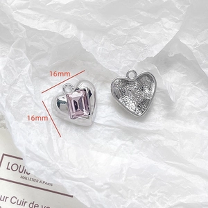 Macro detail of silver heart pendant with pink gemstone and honeycomb texture, 16mm size