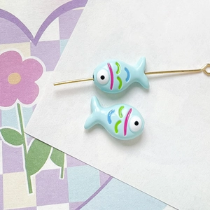 Macro shot of two light blue hand-painted fish beads for DIY jewelry making