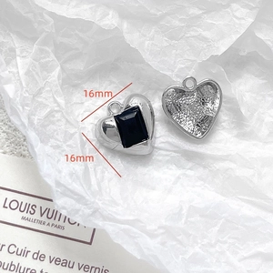 Close-up of 16mm heart-shaped silver metal pendants with black stone and hammered texture