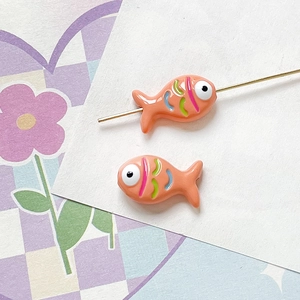 Close-up of hand-painted fish bead with colorful stripes and central hole for DIY jewelry