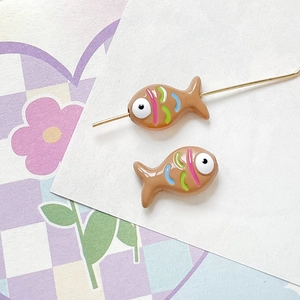 Close-up of hand-painted caramel fish beads with colorful stripes for DIY jewelry making