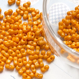 Macro detail of orange peanut-shaped double-hole beads for DIY jewelry making