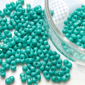 Close-up of vibrant turquoise double-hole peanut beads for DIY jewelry making