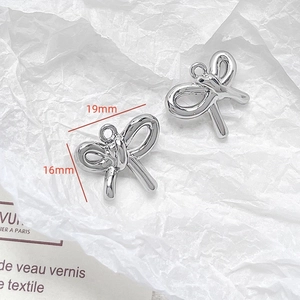 Macro shot of silver bow pendants with 19mm and 16mm size markings for DIY jewelry