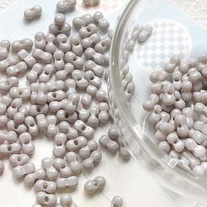 Macro view of grey-purple dumbbell-shaped ceramic beads for DIY jewelry making