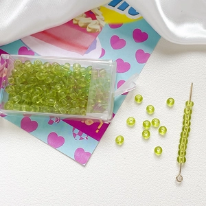Macro detail of 4mm grass green frosted glass beads with a threading needle and storage box