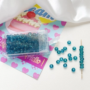 Detailed view of 4mm frosted lake blue glass seed beads with beading needle and organizer box