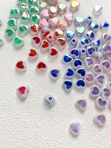 Macro view of iridescent acrylic heart beads with drill holes for DIY jewelry making