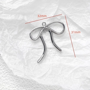 Silver bow jewelry pendant measuring 32mm by 31mm on white paper background