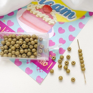 Macro detail of 4mm olive green frosted glass beads with threading needle and case