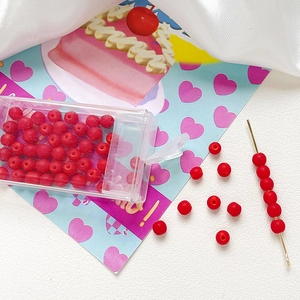 Detailed view of 4mm frosted red glass beads for DIY jewelry making in a plastic storage box