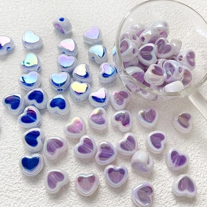 Pearlescent purple and blue acrylic heart beads for DIY jewelry and crafts in a glass