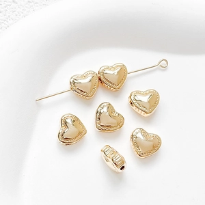 Detailed macro of 14k gold heart-shaped spacer beads with textured edges and side holes