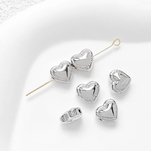 Macro shot of 14k gold plated heart spacer beads on a needle for DIY jewelry making