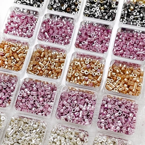 Imported polished glass bugle beads in a clear storage box for DIY jewelry making