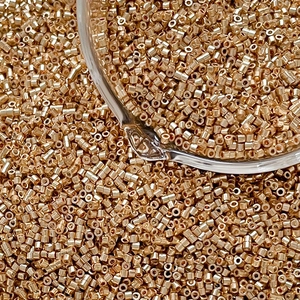 Macro shot of metallic gold glass Delica beads for DIY jewelry and intricate weaving