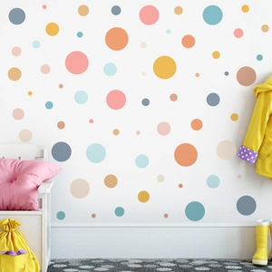 Detail von bunten Punkt-Wandtattoos an einer weißen Wand in einem gemütlichen Kinderzimmer