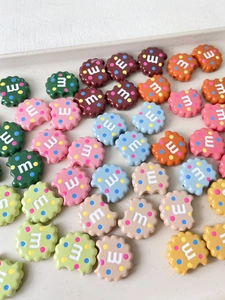 Makroansicht bunter Keksperlen aus Harz mit Buchstabe M für DIY-Schmuckherstellung