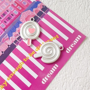 Dettaglio di ciondoli a lecca-lecca DIY con cuore rosa e spirale su carta a righe
