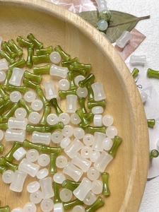 Dettaglio di perle in vetro verde e bianco a forma di bambù per gioielli fai-da-te