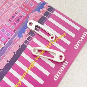 Macro di ciondoli a spilla da balia in argento lucido su una carta decorativa rosa