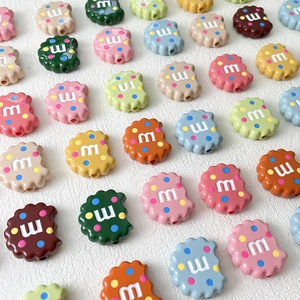 Bunte perlen in keksform mit m-buchstaben und punkten für diy bastelprojekte