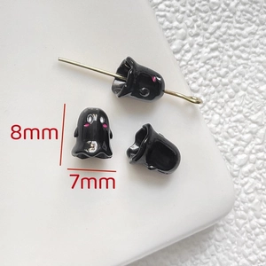 Macro detail of 8x7mm black ghost charms with pink cheeks for DIY jewelry making