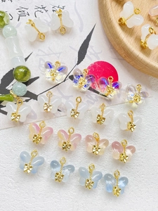 Macro detail of colorful glass butterfly charms with golden metal bow accents for DIY jewelry