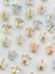 Close-up of translucent butterfly charms with gold bow accents and metal loops for DIY jewelry