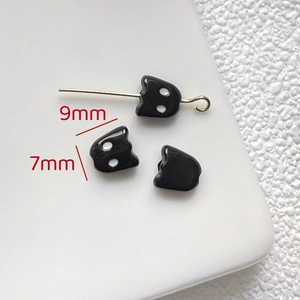 Macro shot of three small black cat charms showing 9mm by 7mm dimensions for jewelry DIY