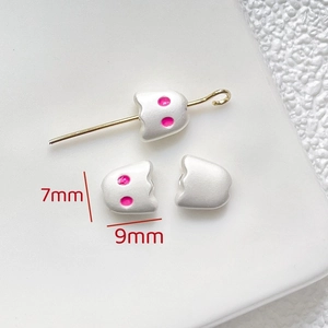 Macro detail of 7x9mm white ghost beads with pink dot eyes and gold pin for DIY jewelry