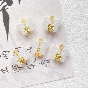 Macro detail of butterfly jewelry charms in white resin with golden accents for DIY