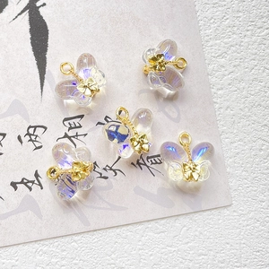 Macro detail of five iridescent butterfly charms with gold metal loops on calligraphy paper