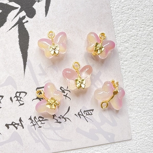 Close-up of five delicate pink and yellow gradient glass butterfly pendants for jewelry