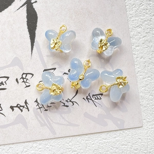 Close-up of translucent blue butterfly charms with gold metal loops for DIY jewelry
