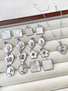 Detalle de colgantes de corazón en plata con nácar, circonitas y grabados de flores