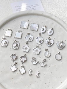 Detalle de colgantes plateados de corazón y geométricos con incrustación de nácar blanco