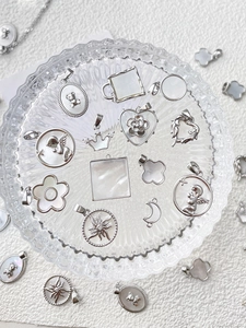 Primer plano de colgantes de corazón y geométricos en plata con incrustaciones de nácar