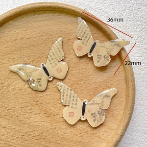 Detailed view of three butterfly DIY pendants with Chinese calligraphy on wood tray