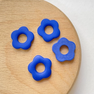 Détails de quatre fleurs en résine bleu marine mat pour bricolage sur un plateau en bois