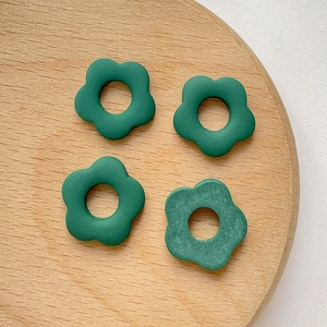 Détail de quatre breloques de fleurs vertes sur un support rond en bois naturel