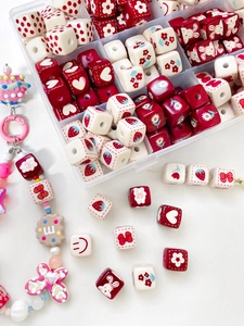 Vue macro de jolies perles cubes DIY rouge et crème avec motifs fraise et lapin