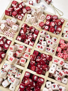 Vue macro de perles DIY rouges et blanches avec motifs lapin et cerise en boîte bois